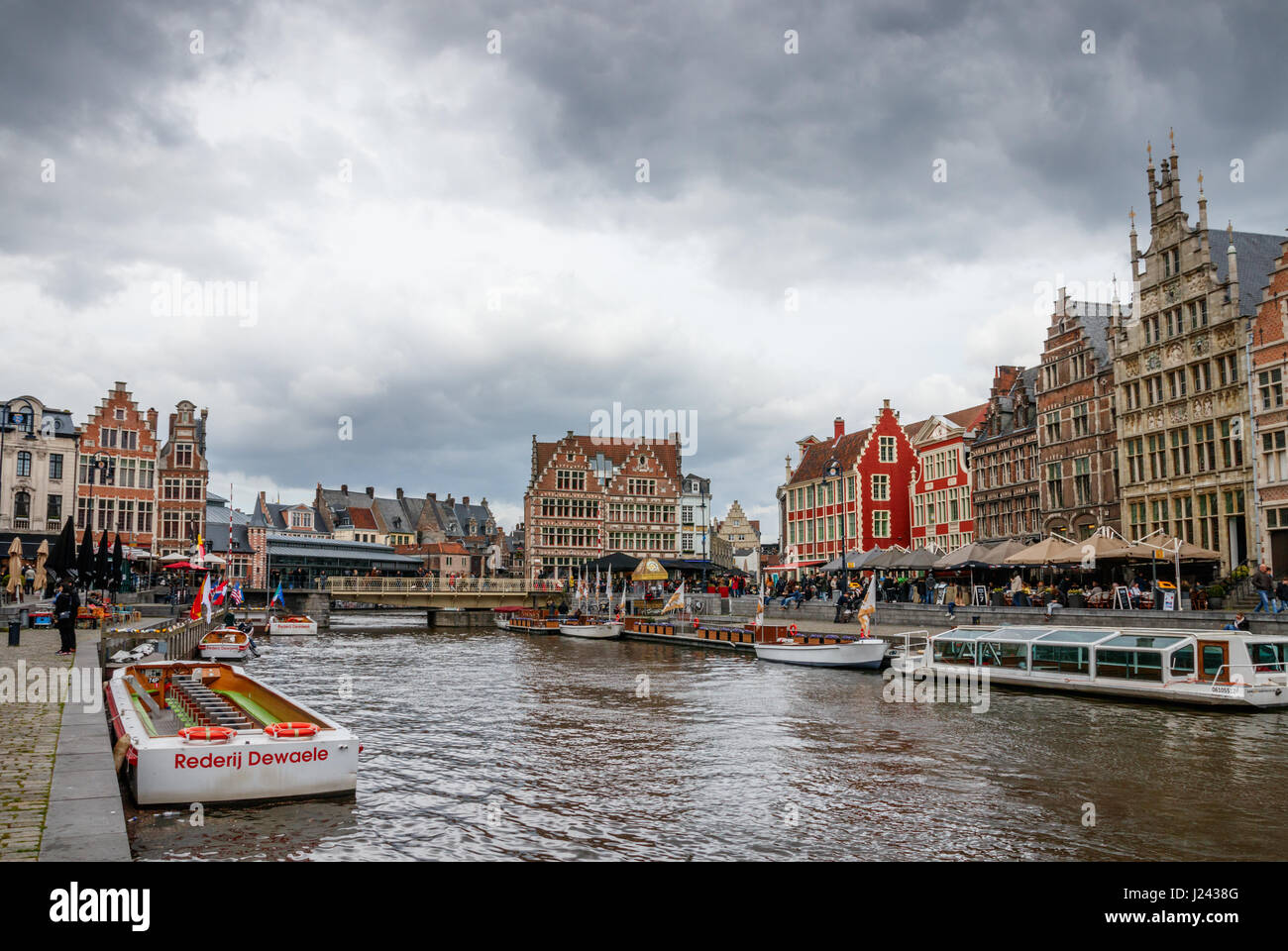 View of Graslei (Grass Quay) and Korenlei (Corn Quay) with medieval buildings, tourist boats and unidentified tourists on a cloudy day. Ghent, Belgium Stock Photo