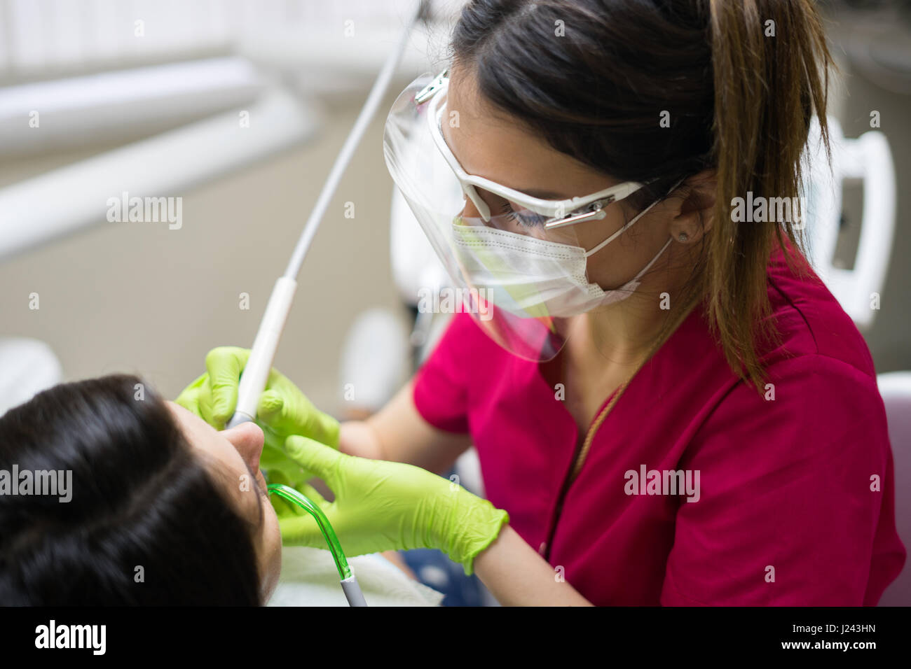 Female dentist cleaning teeth of a beautiful patient woman in dental