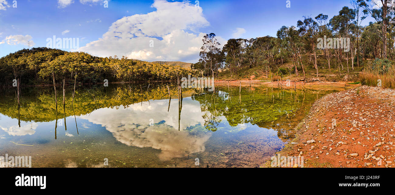 Lake lyell still waters along Coxs river on a bright sunny day when white clouds reflect in blue water between hills and gumtrees. Stock Photo