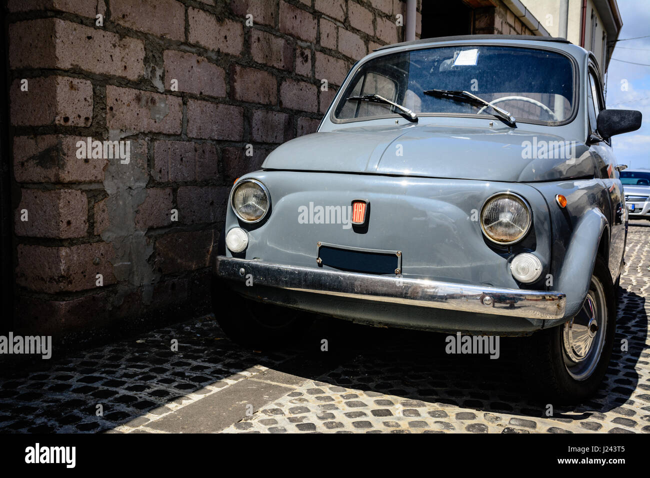 Old grey vintage car parked in the narrow pebbled street of Tinnura