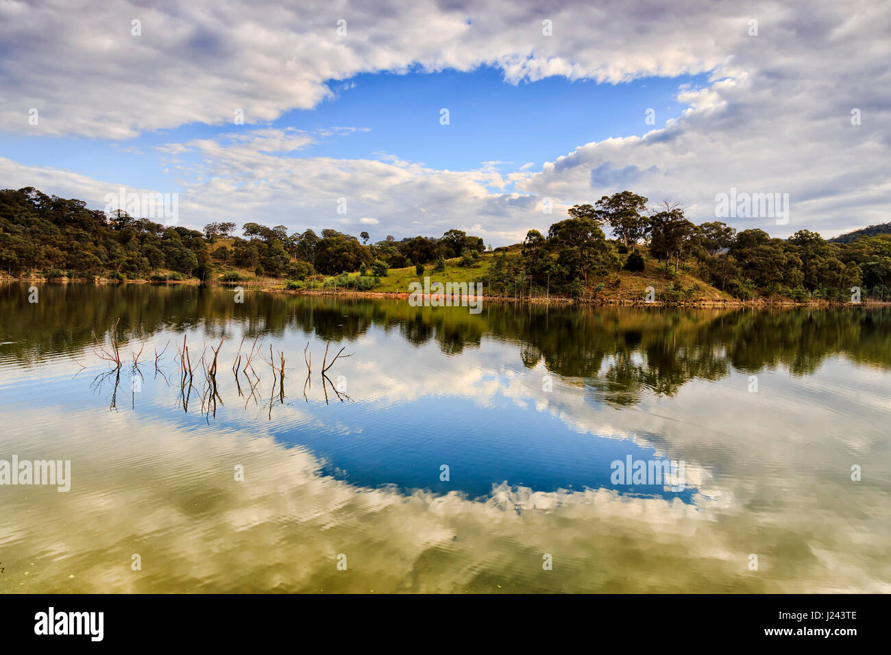 Lake Lyell on Coxs river in Blue Mountains national park on a sunny summer day with blue sky and clouds reflecting in still waters between hilly shore Stock Photo