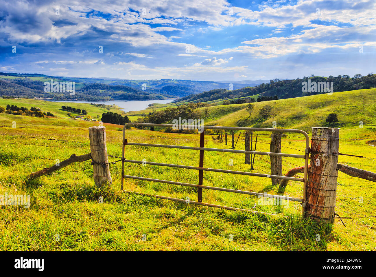 Grazing hill sides surrounding Lake Lyell on Coxs river in Australian Blue Mountains country. Entry gate to the green pasture under warm sun light. Stock Photo