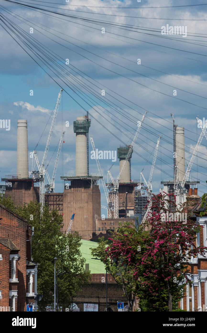 London, UK. 25th April, 2017. The cranes and chimneys loom over a terraced residential street in Clapham old towmn- The reconstruction of Battersea power station continues ion a bright but crisp spring day. London 25 Apr 2017. Credit: Guy Bell/Alamy Live News Stock Photo