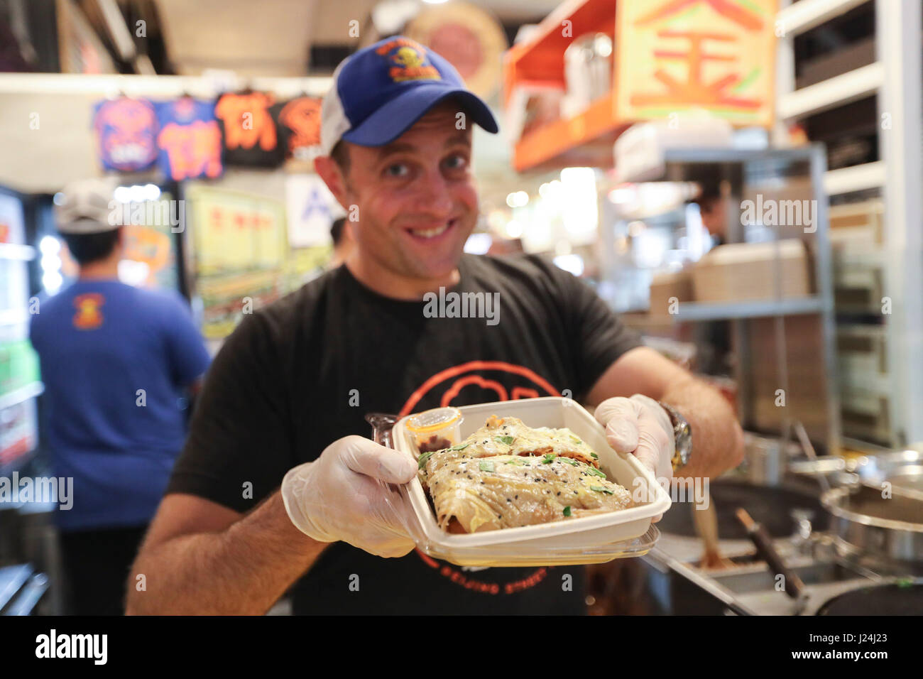 New York, USA. 25th Apr, 2017. Brian Goldberg shows a Jianbing at the kiosk of Mr. Bing in UrbanSpace food court in New York, the United States, April 17, 2017. UrbanSpace in midtown New York is a place white-collars come for lunch during their workdays. For the past a few months, customers have always lined up before a kiosk under a banner with Chinese characters. What this kiosk sells is a very authentic Chinese food in north China -- Jianbing, or the Chinese crepe. Credit: Xinhua/Alamy Live News Stock Photo