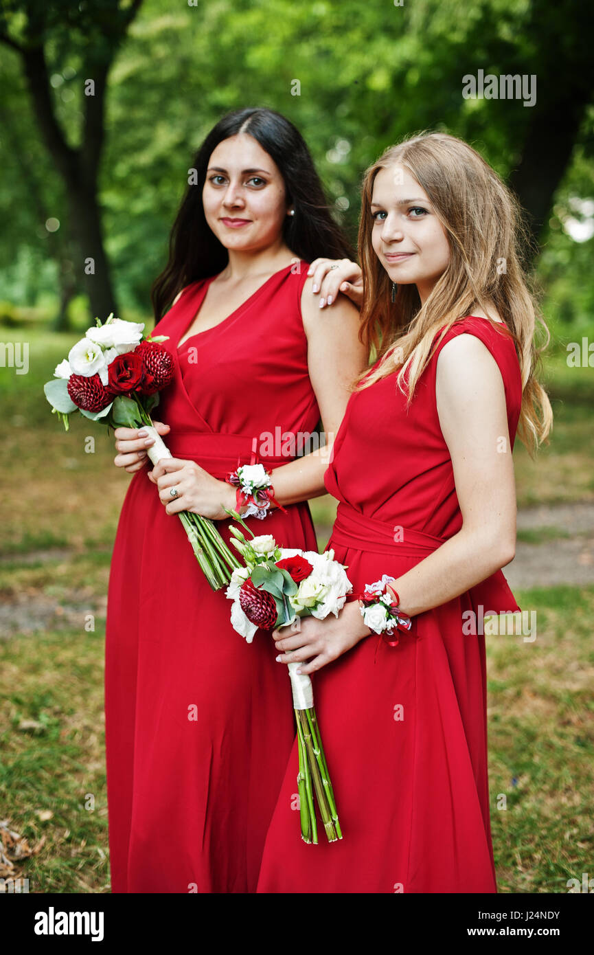 Two girls bridesmaids at red dresses with wedding bouquets Stock Photo ...