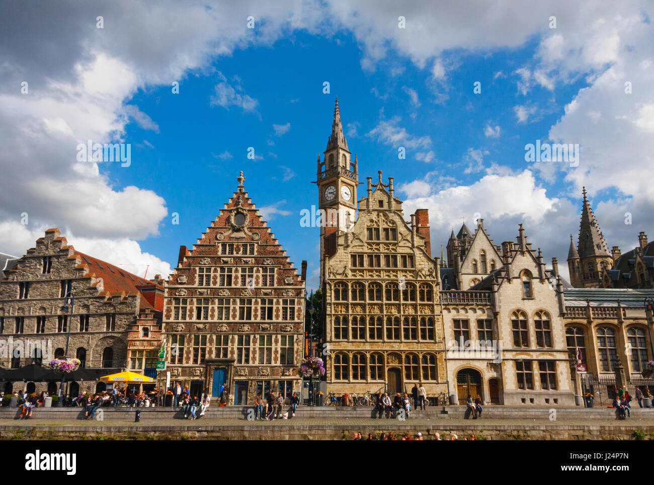 View of Graslei (Grass Quay) with medieval buildings and unidentified tourists under a blue sky with clouds. Ghent, Belgium. Stock Photo