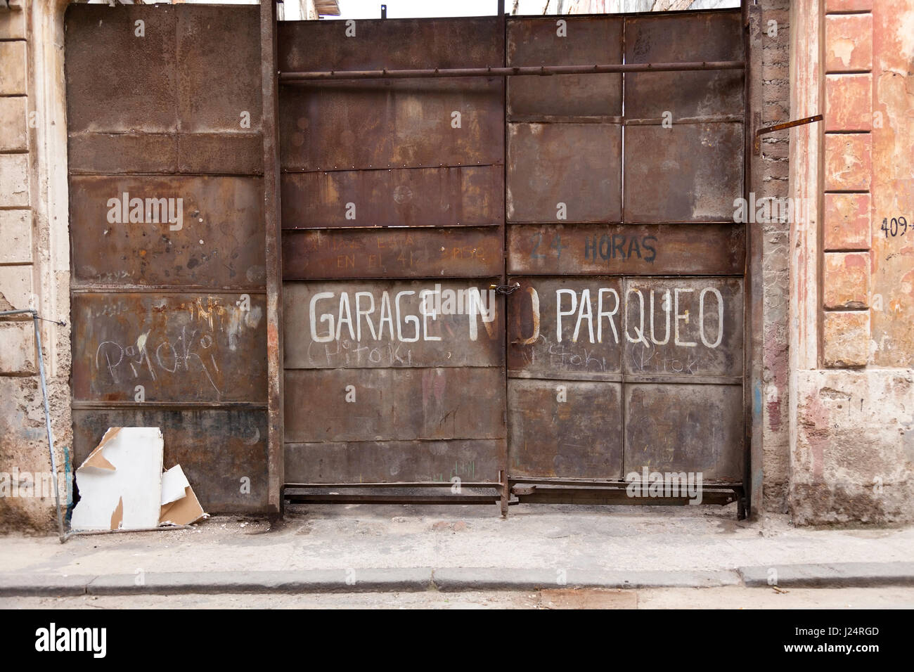 A no parking sign painted onto a rusty garage door in Havana, Cuba. Stock Photo