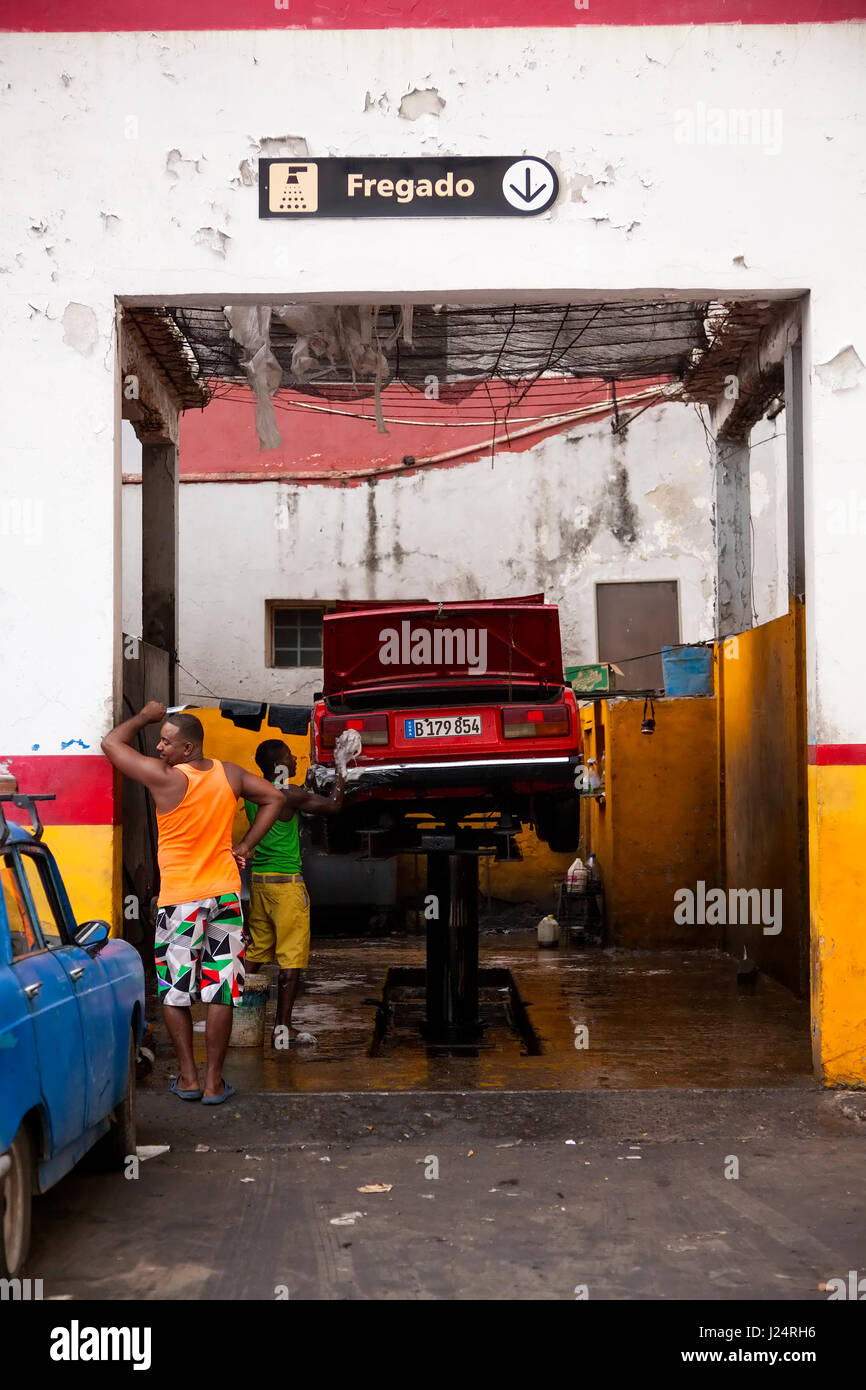 A man washing a car inside an automotive garage in Havana, Cuba. Stock Photo