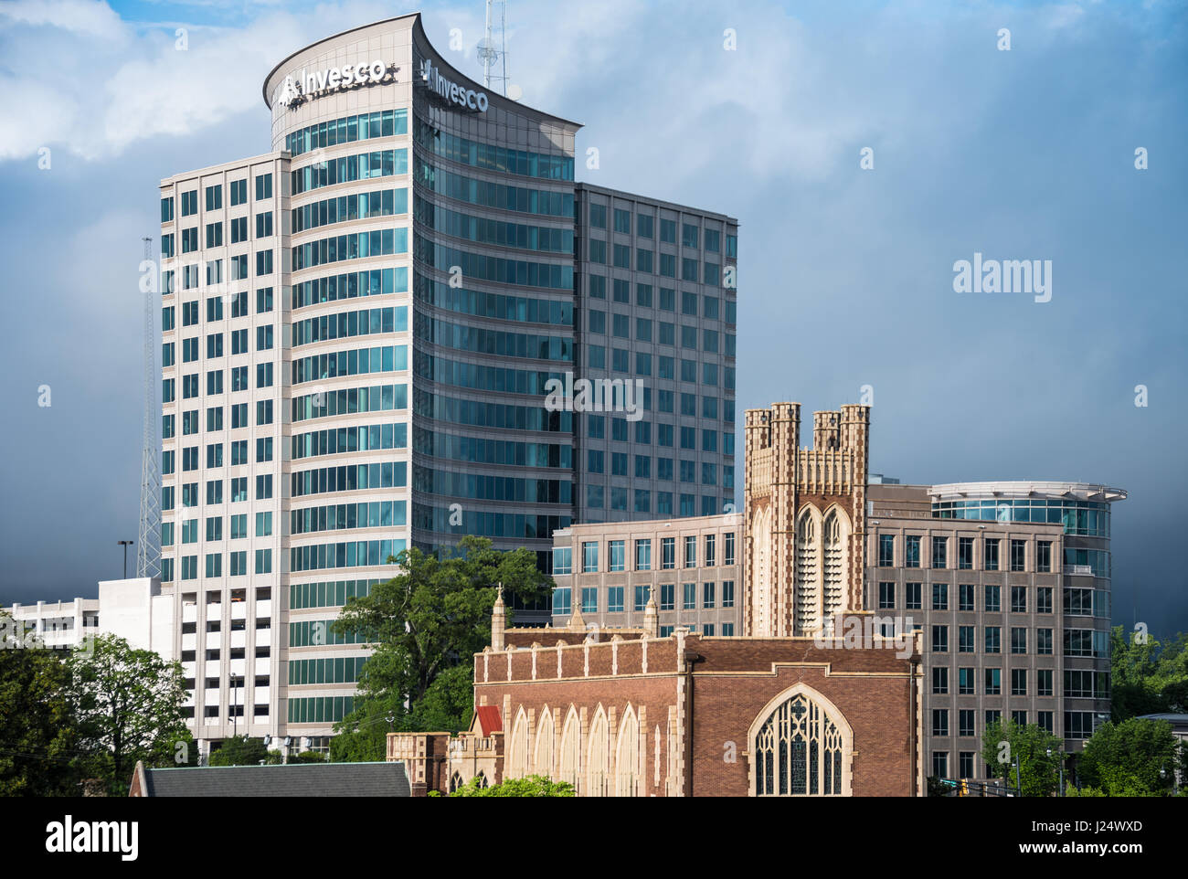 Architectural contrast along the Atlanta, Georgia skyline where the modern Invesco building towers above the Peachtree Christian Church in Midtown. Stock Photo