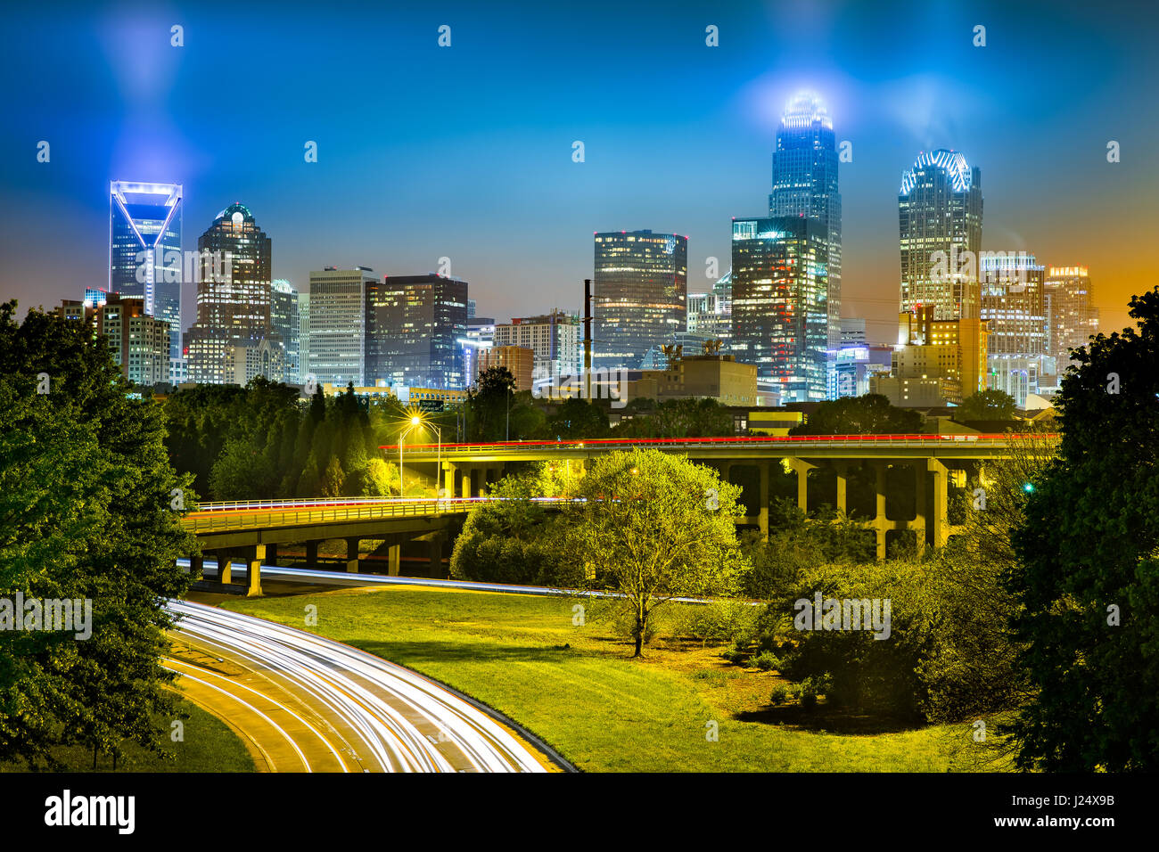 Traffic light trails in Charlotte, North Carolina. The city skyline glows on a foggy night. Stock Photo