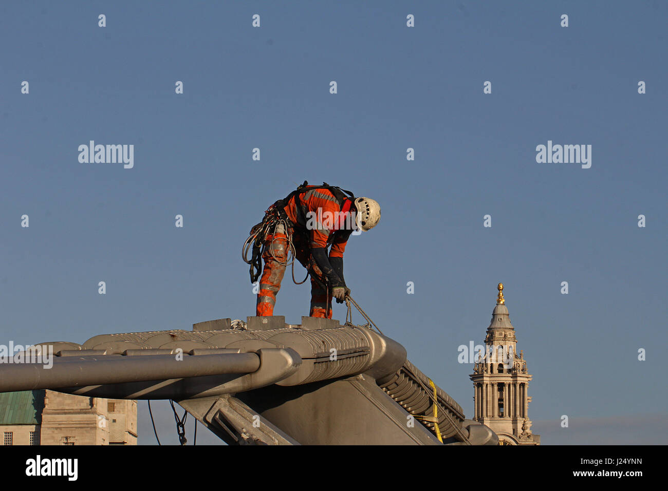 A bridge engineer, wearing a safety harness, on top of the Millennium Bridge, London Stock Photo