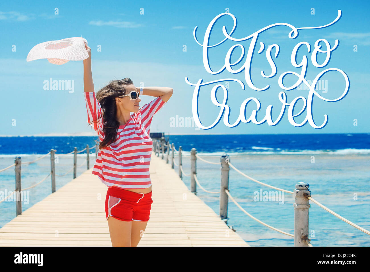 happy woman standing on pier with big white hat and text Lets go travel. Calligraphy lettering hand draw Stock Photo