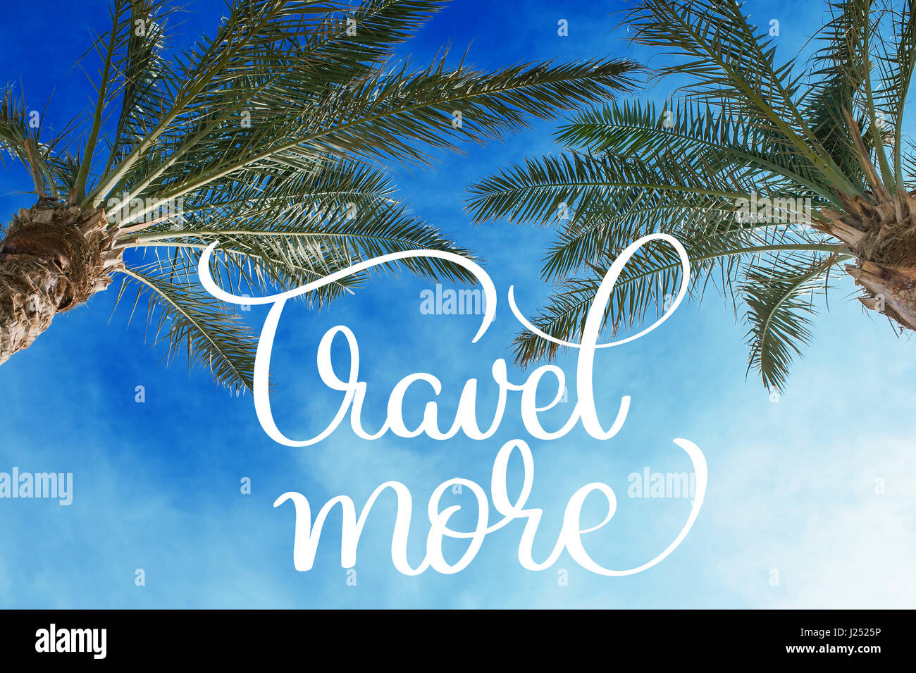 Two palm treetops against a sunny sky and Travel more text. Calligraphy lettering hand draw Stock Photo