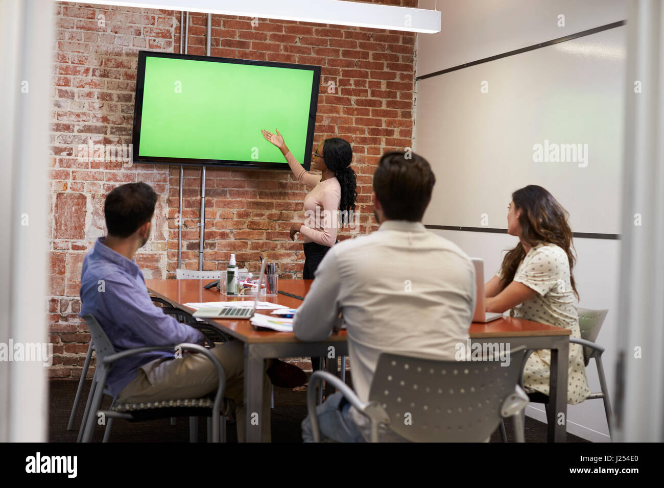 Businesswoman Standing By Screen To Deliver Presentation Stock Photo