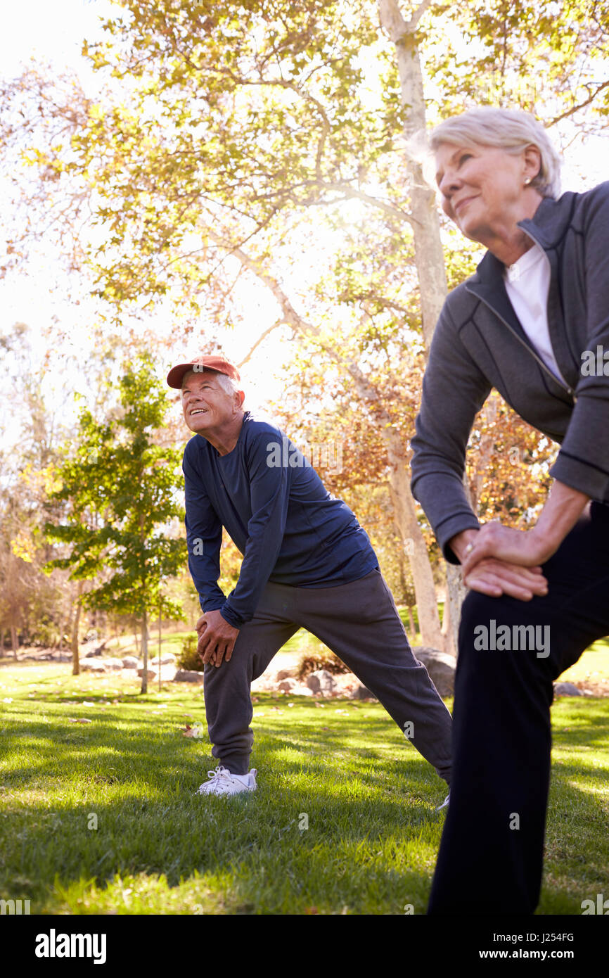 Senior Couple Stretching Whilst Exercising Together In Park Stock Photo