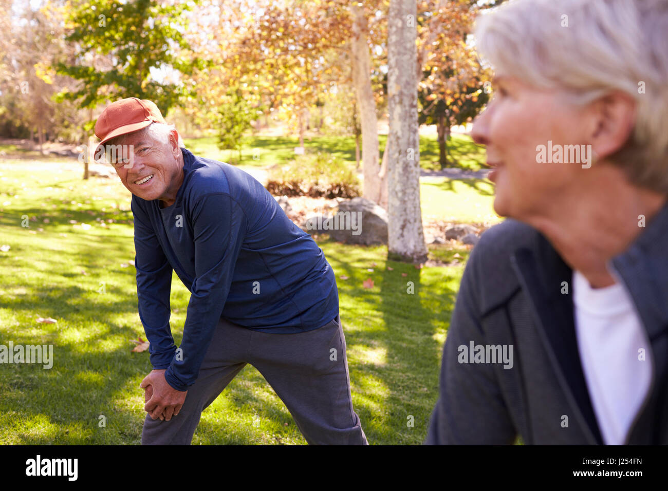 Senior Couple Stretching Whilst Exercising Together In Park Stock Photo
