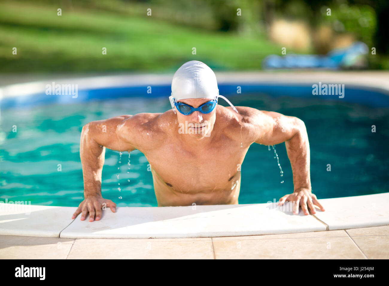 Handsome swimmer with cap and goggles in swimming pool Stock Photo