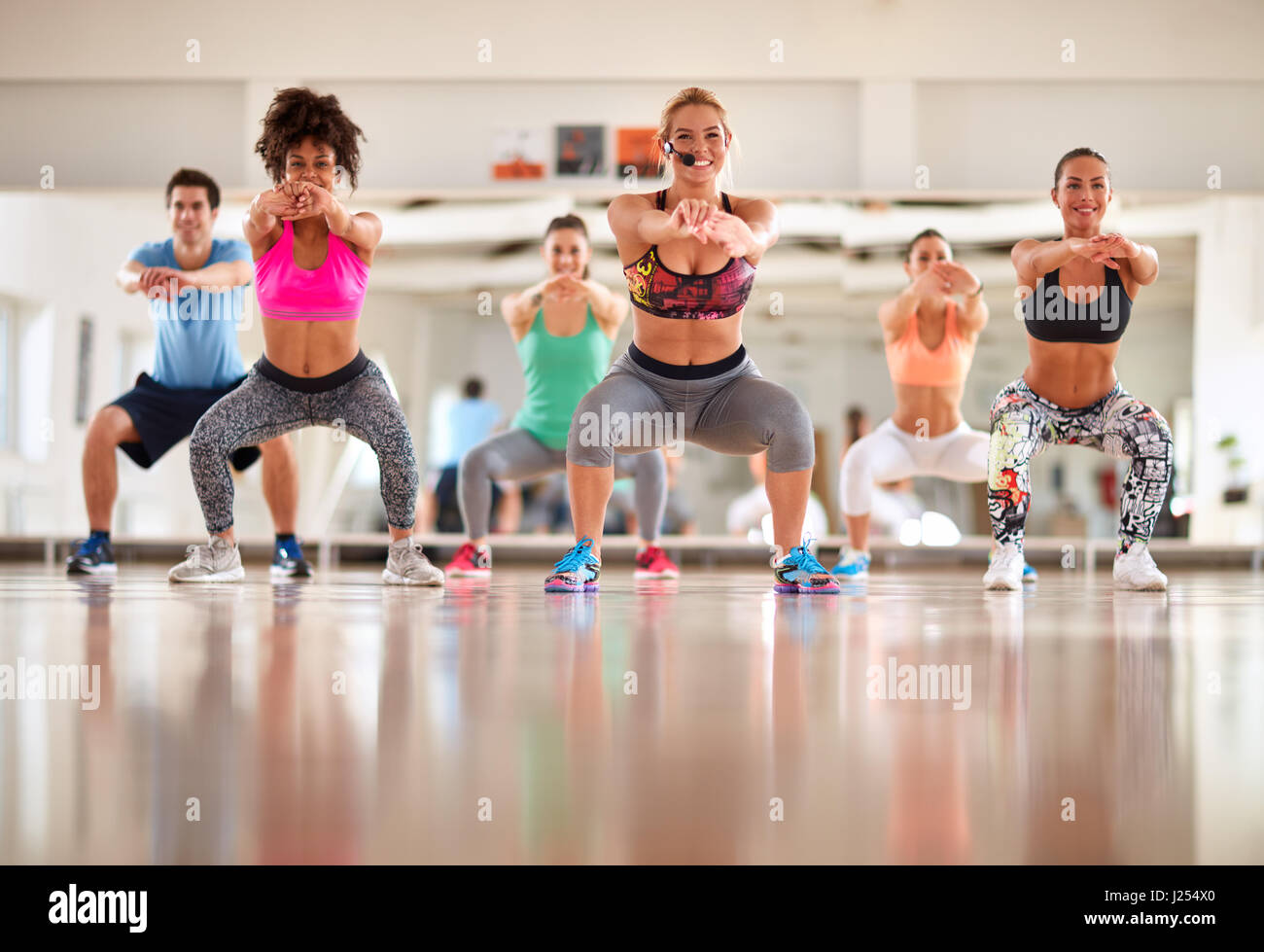 Young female instructor with fitness group doing exercises for shaping body Stock Photo