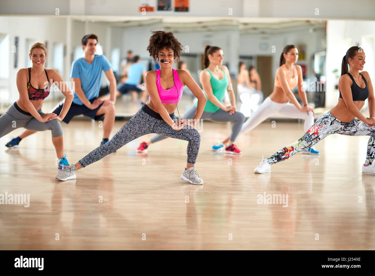 Group of exercisers with female trainer doing exercises for shaping