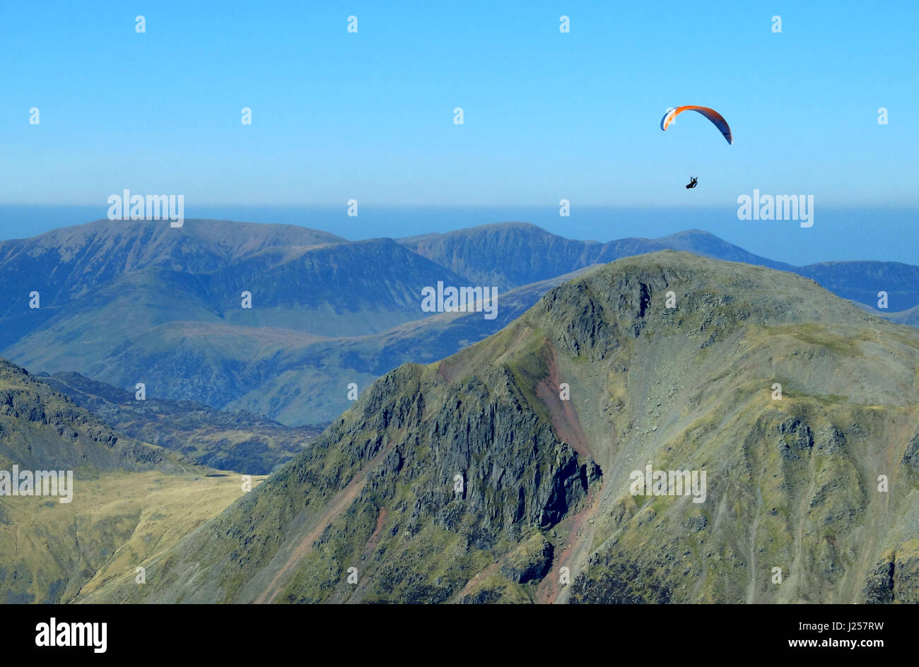 Paraglider launching from the peak of Scafell Pike and paragliding over the fells of the English Lake District, Cumbria Stock Photo