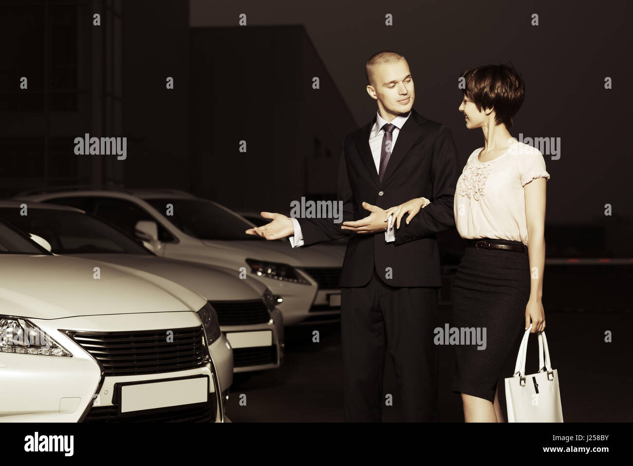 Young couple collecting new car at dealership lot Stock Photo