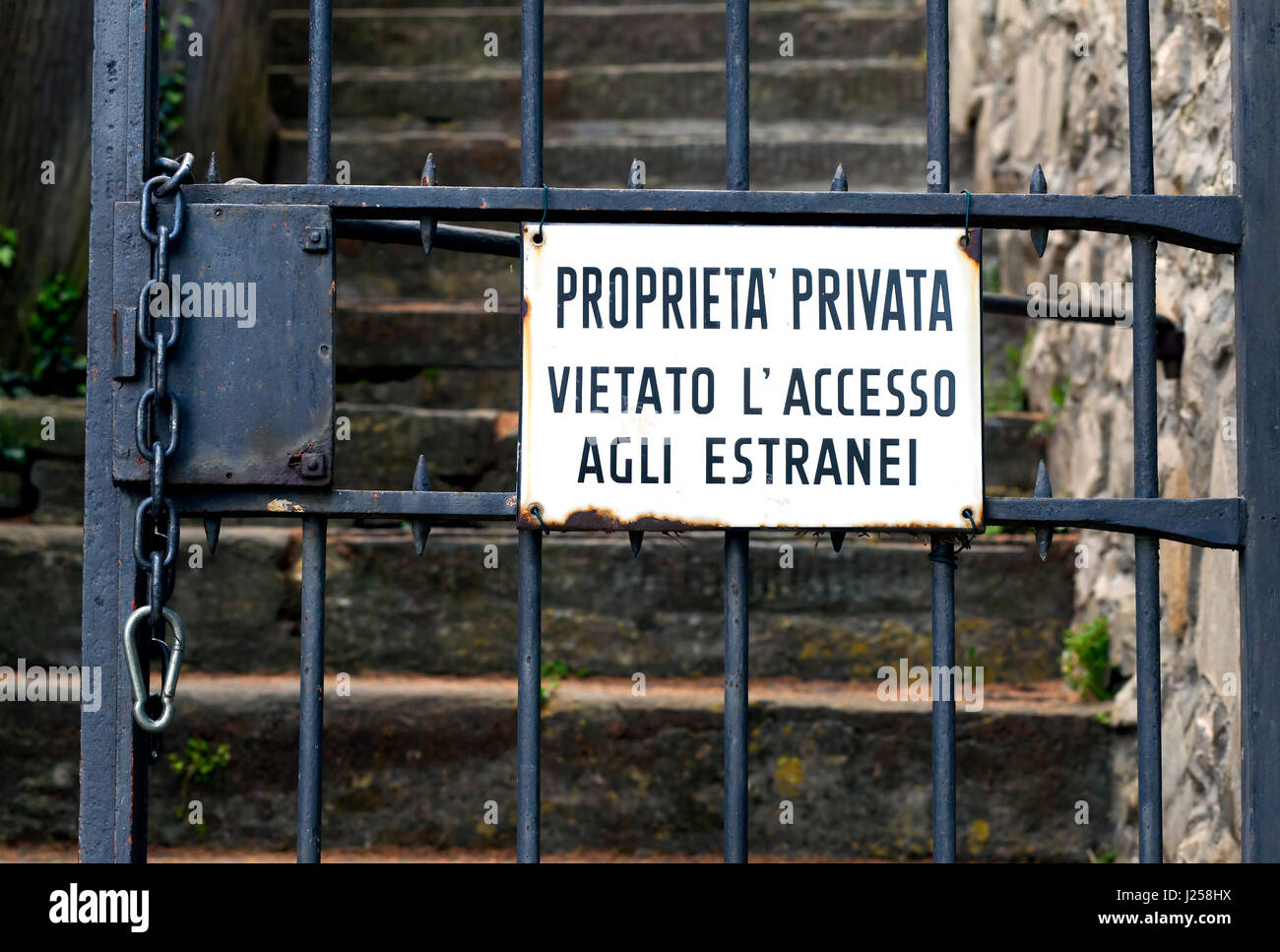 Vintage image of "Private property" sign in Italian on an iron bar gate
