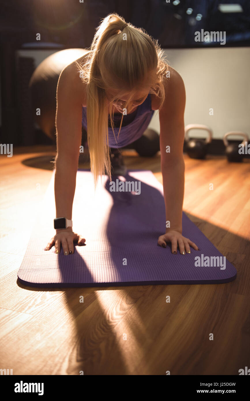 Fit woman performing fitness exercise on a gymnastic mat in the gym ...