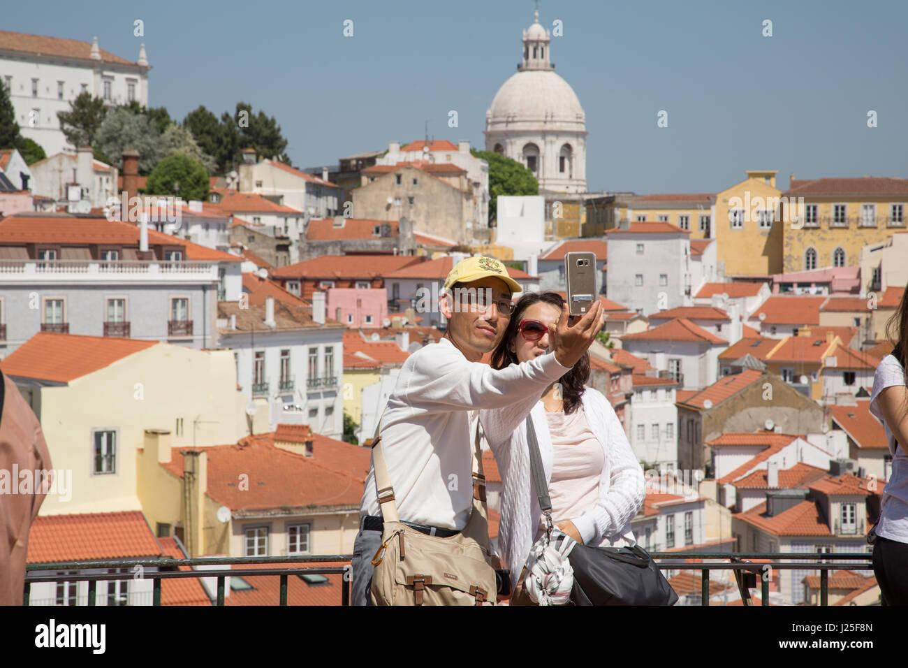 A couple taking a selfie on a mobile phone with the city of Lisbon in the background. Stock Photo