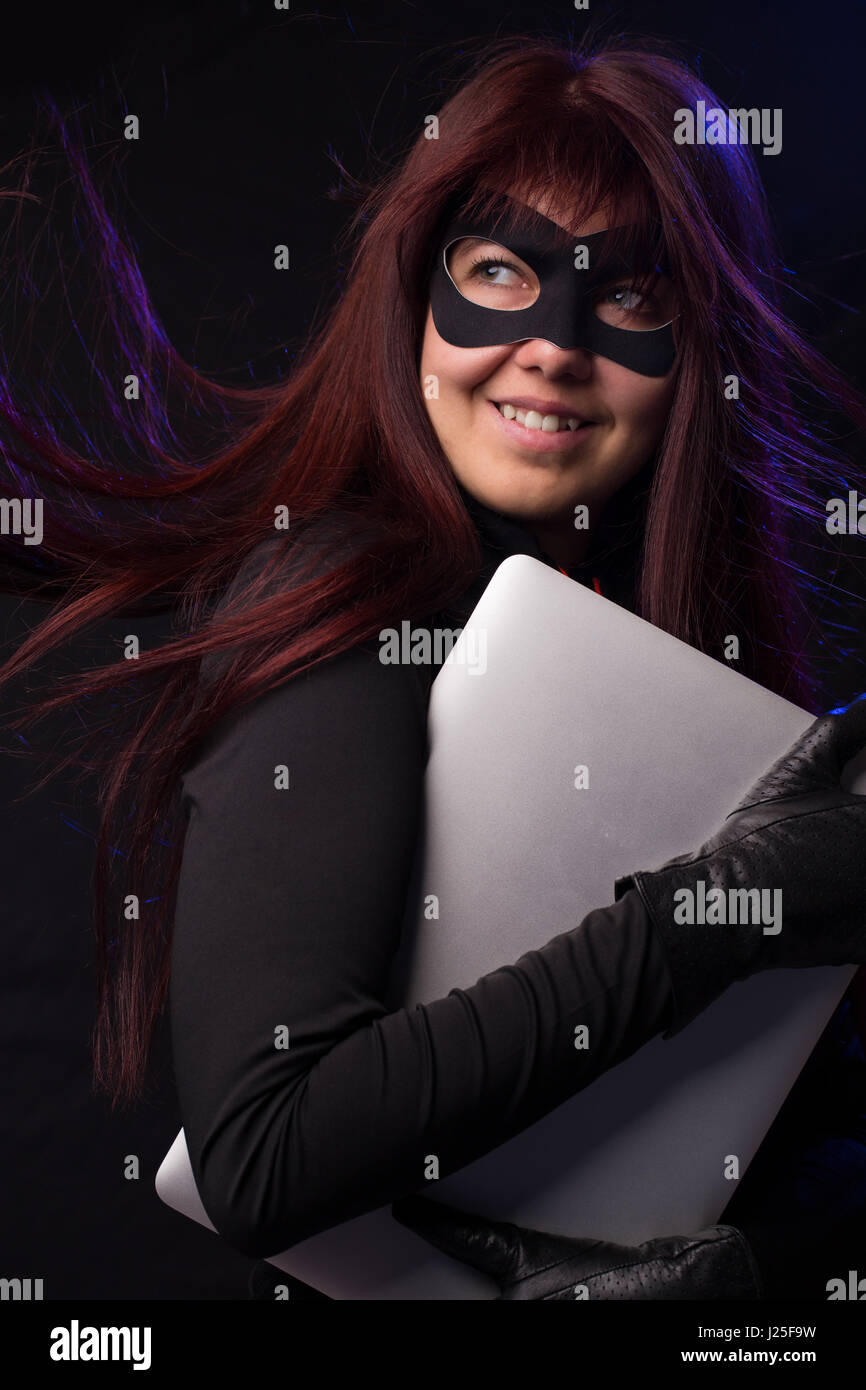 Thief in mask holds laptop Stock Photo - Alamy