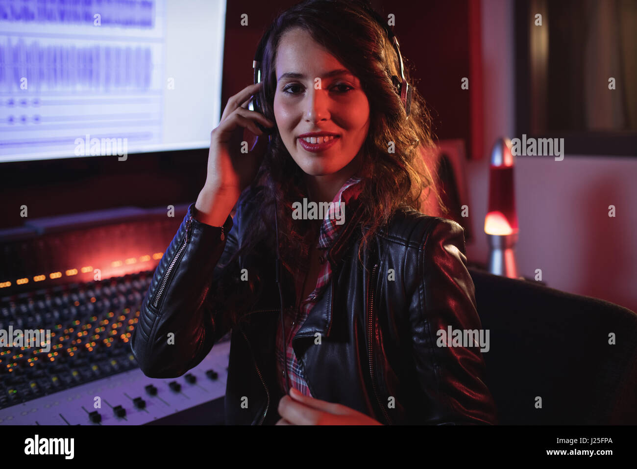 Female audio engineer listening music on headphones in recording studio