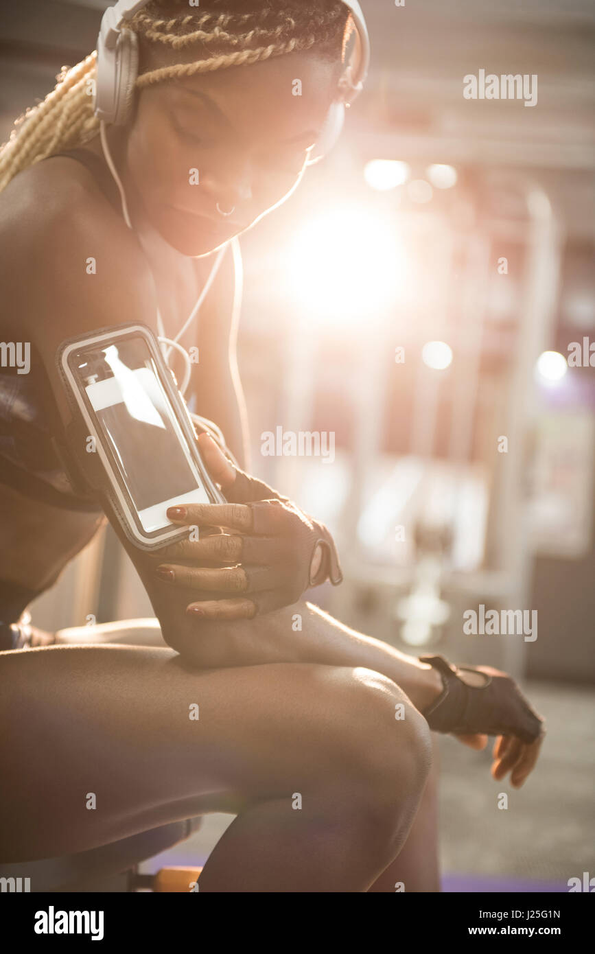 Fit woman using smartphone in armband at gym Stock Photo