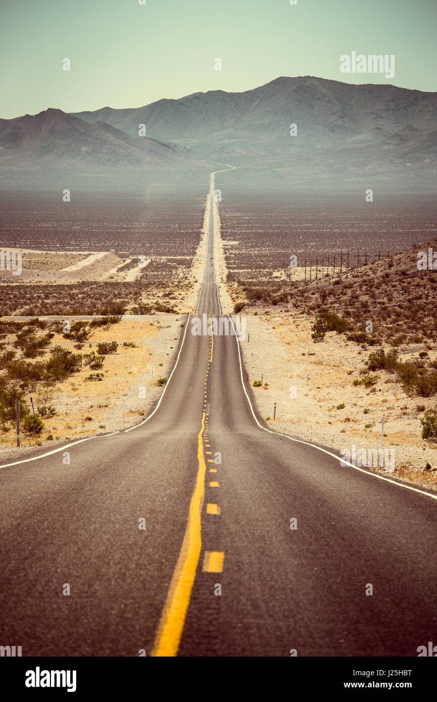 Classic panorama view of an endless straight road running through the barren scenery of the American Southwest in summer Stock Photo