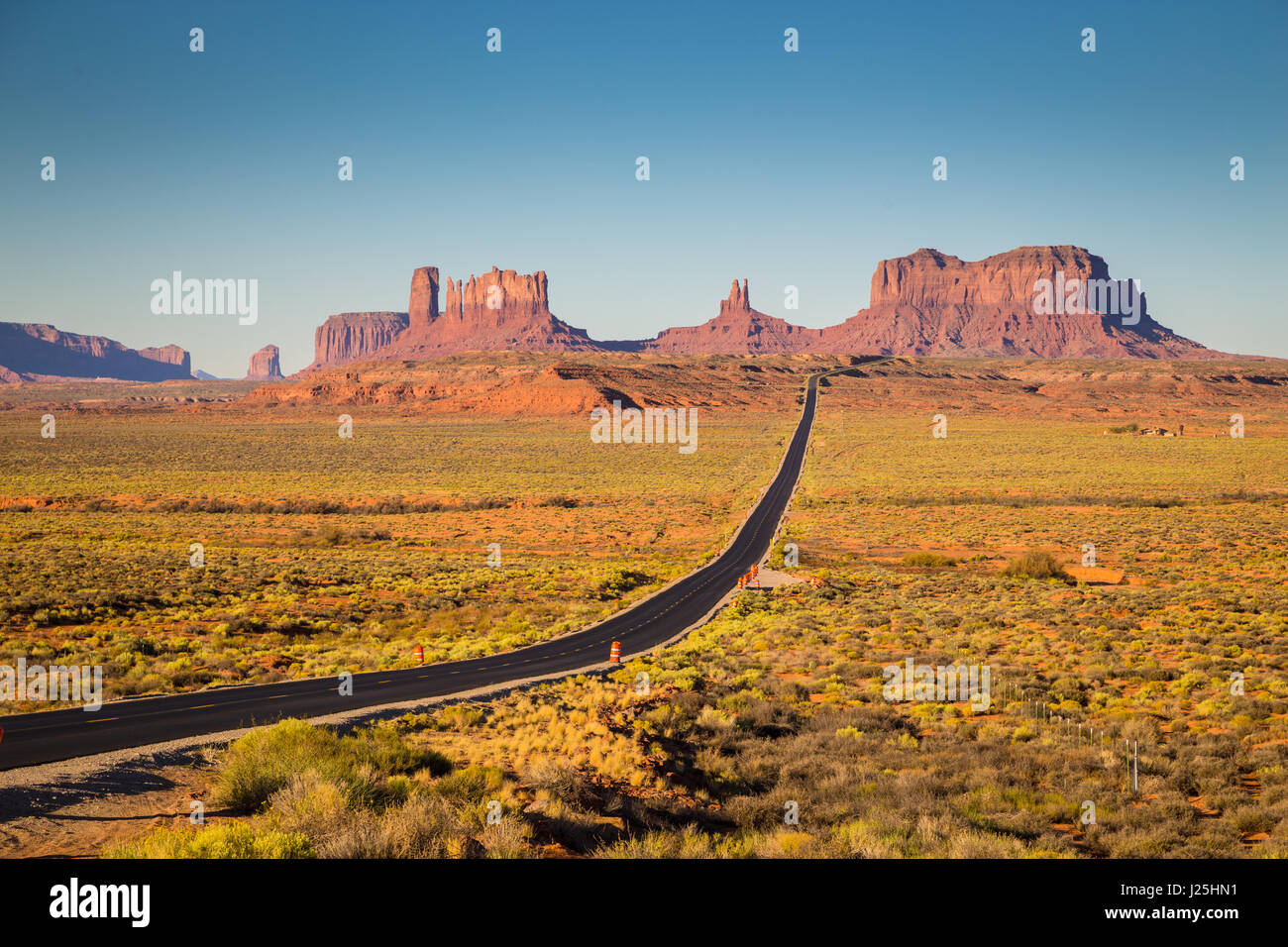 Classic panorama view of historic U.S. Route 163 running through famous Monument Valley in beautiful golden evening light at sunset, Utah, USA Stock Photo