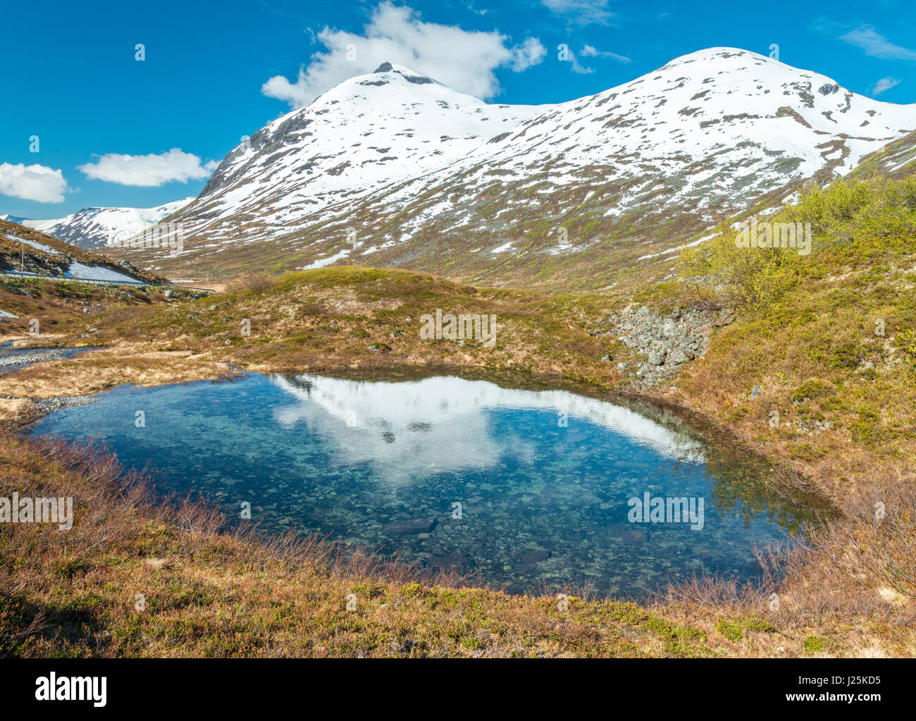 Alpine tarn, pond reflects snowcapped mountains on the other side of the Troll Wall, Norway Stock Photo