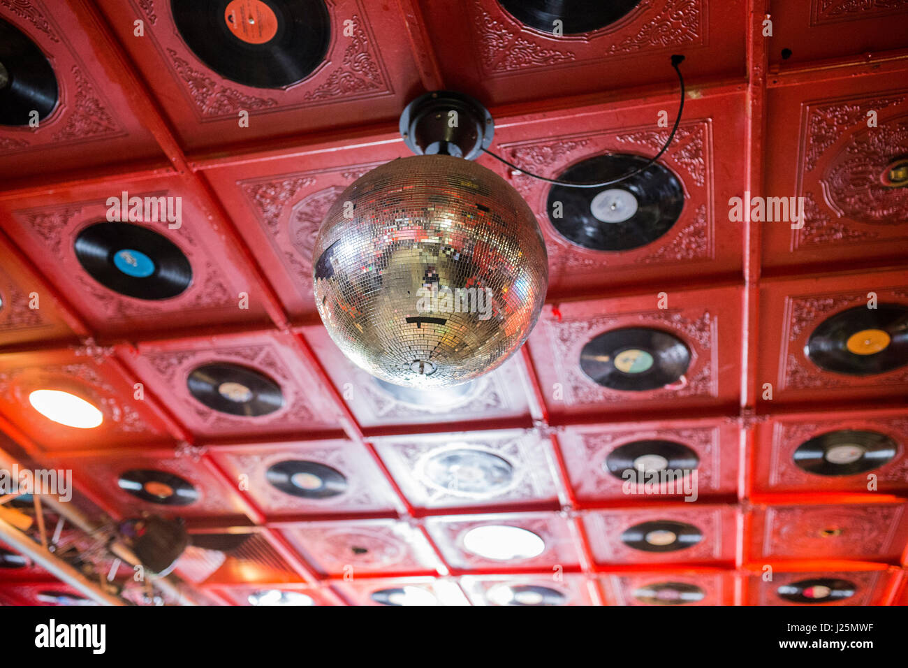 Detail of mirror ball attached to red ceiling with 12' vinyl records embedded in it, in the main room at Molotow club in Hamburg. Stock Photo