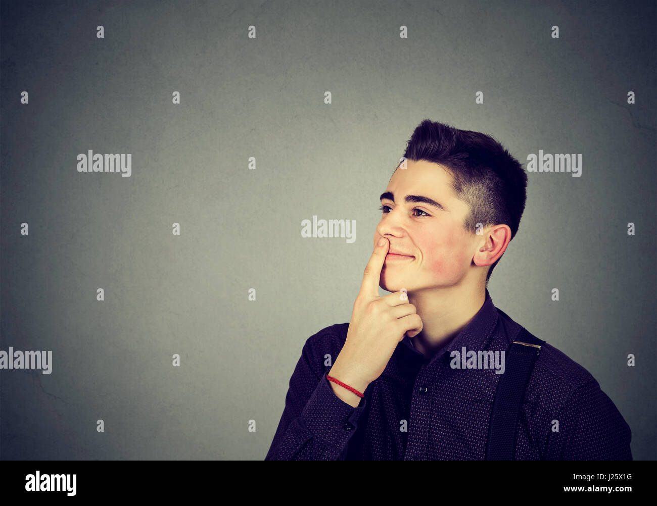 Portrait of a handsome young man thinking isolated on gray background Stock Photo