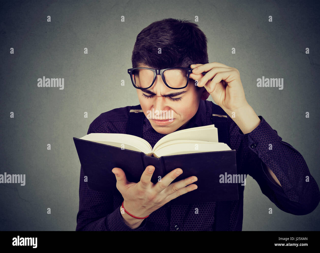 Closeup young man with eye glasses trying to read book, having