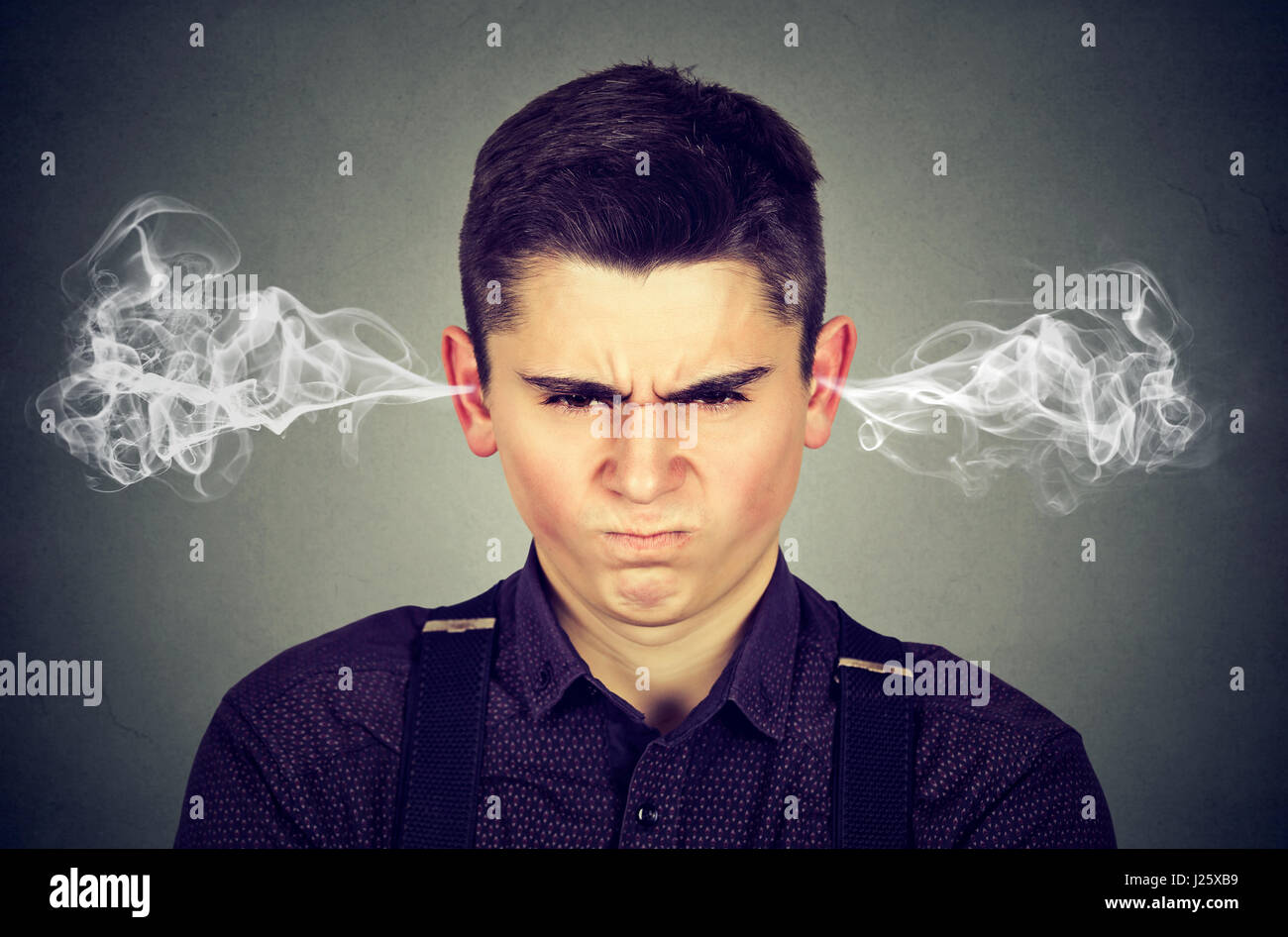 Angry young man, blowing steam coming out of ears, about to have nervous breakdown isolated on gray background. Negative human emotions facial express Stock Photo