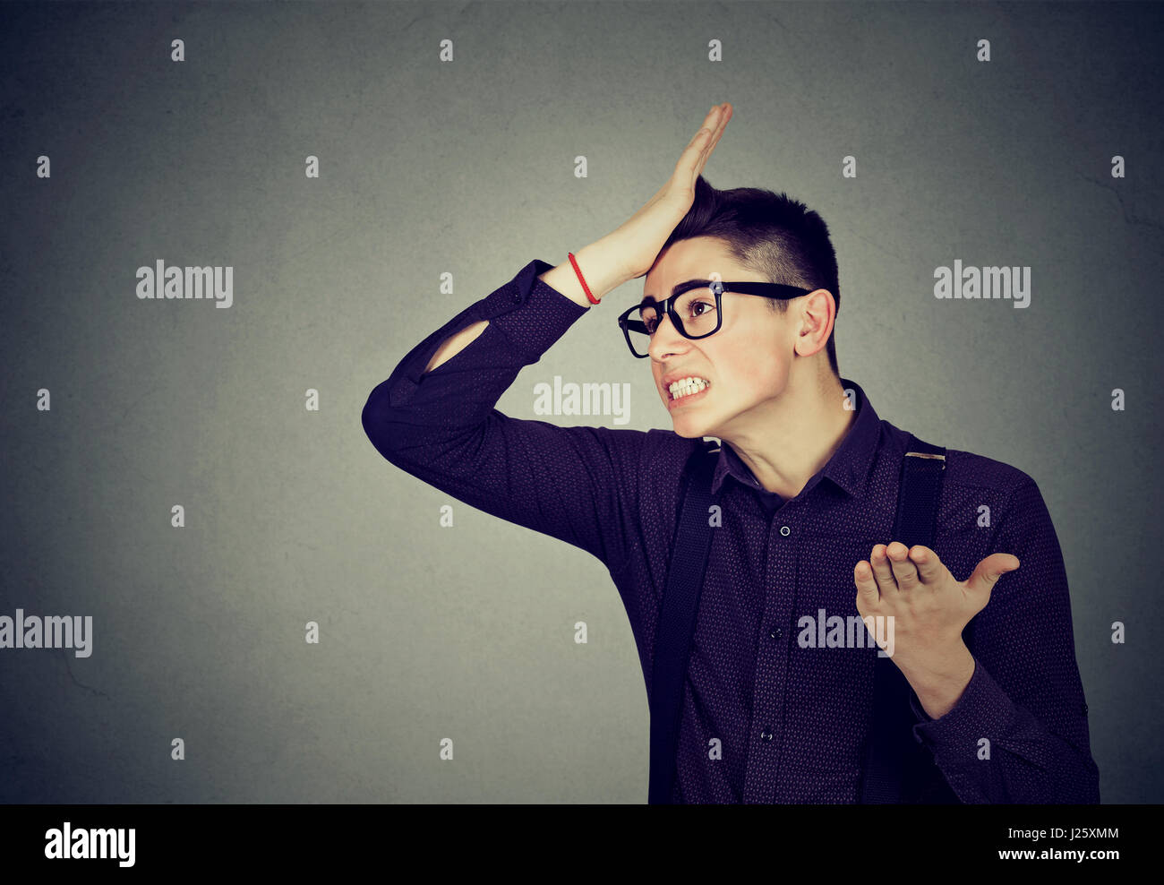 Regrets wrong doing. Silly young man, slapping hand on head having duh moment isolated on gray background. Human emotion facial expression feelings an Stock Photo