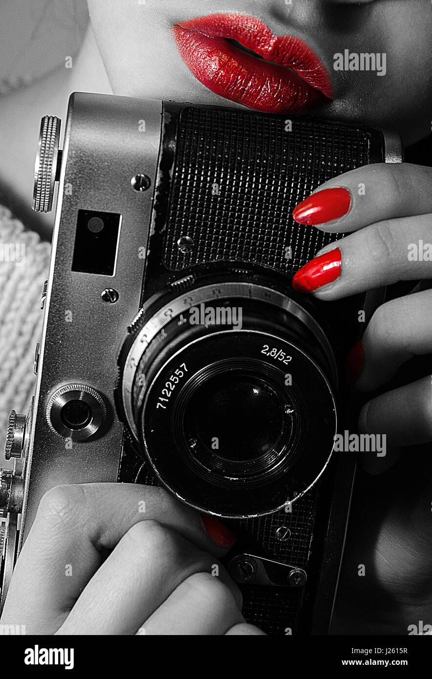 Female hands holding retro camera. Blackandwhite photo, red lips, red