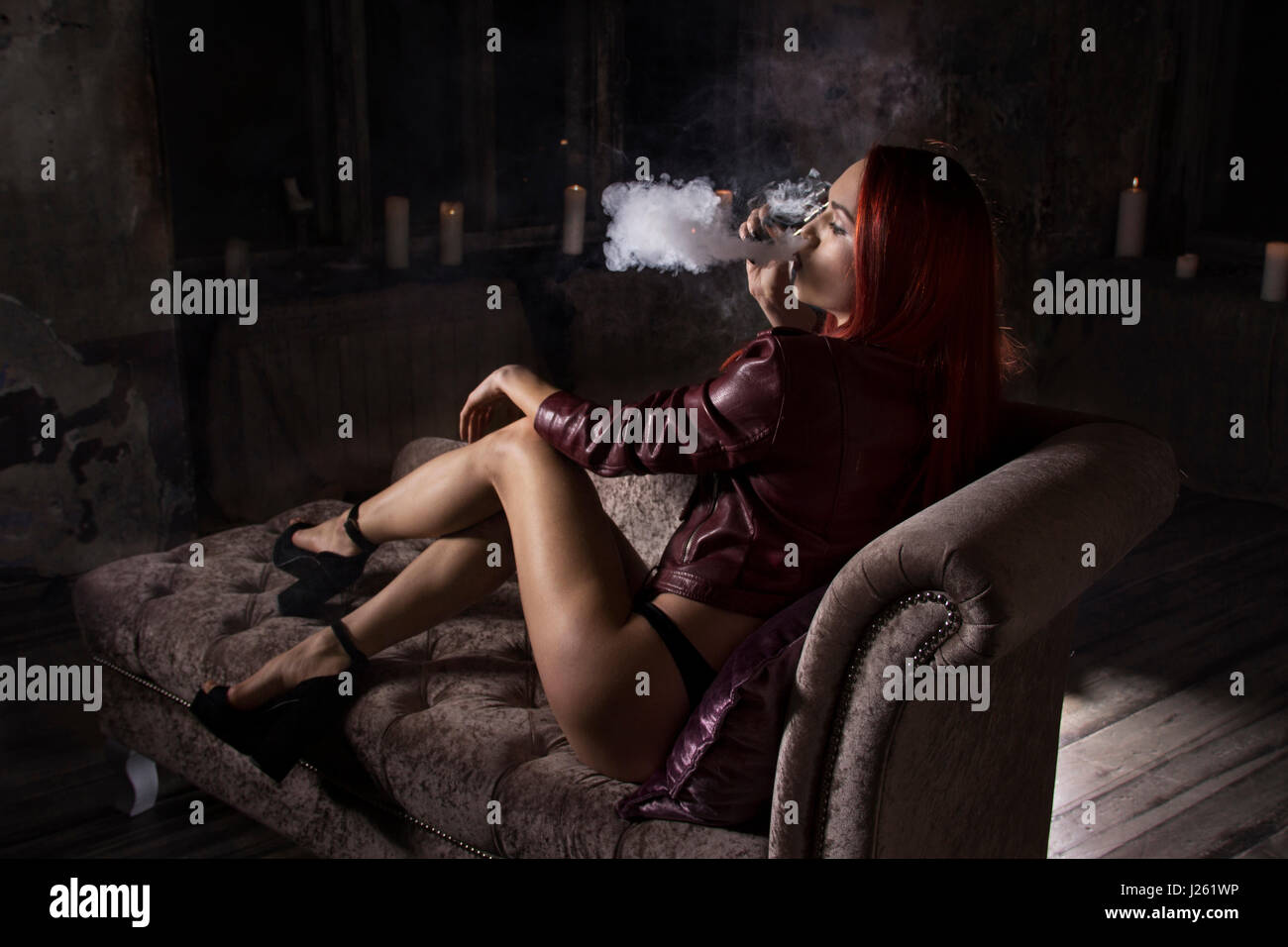 sexy woman smoking electronic cigarette and lying on the sofa, vape mod  concept Stock Photo - Alamy