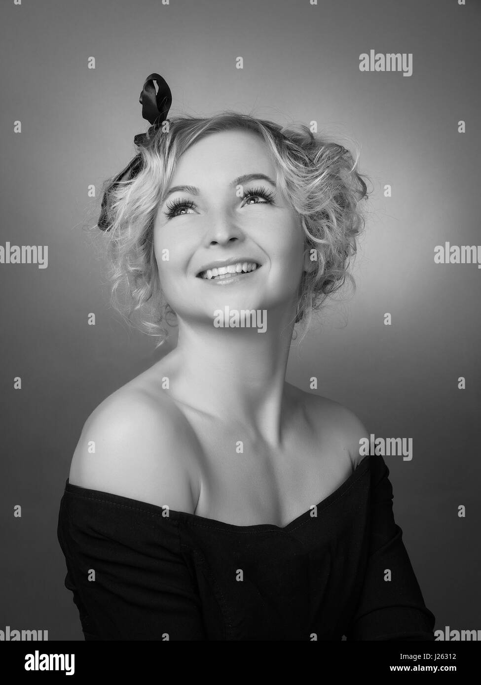 Beautiful girl in a black dress on a gray background Stock Photo - Alamy
