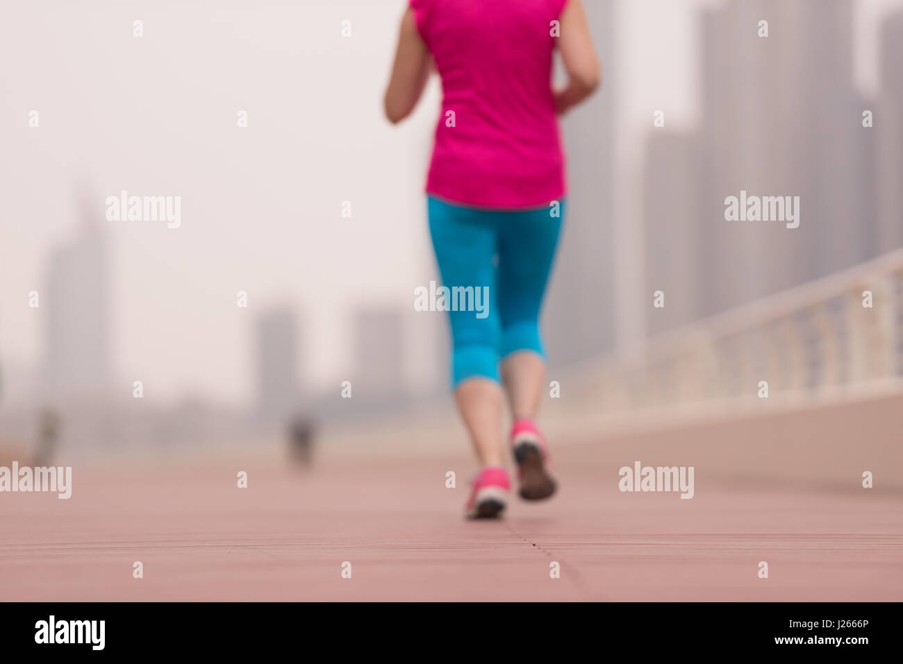 very active young beautiful woman busy running on the promenade along ...