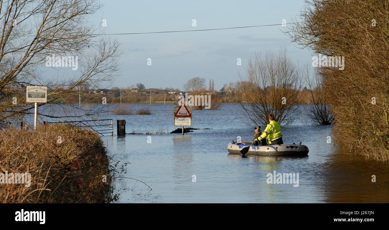 Couple paddling a dinghy on a severely flooded and closed road on Curry Moor, North Curry, Somerset Levels, UK, February 2014. Stock Photo