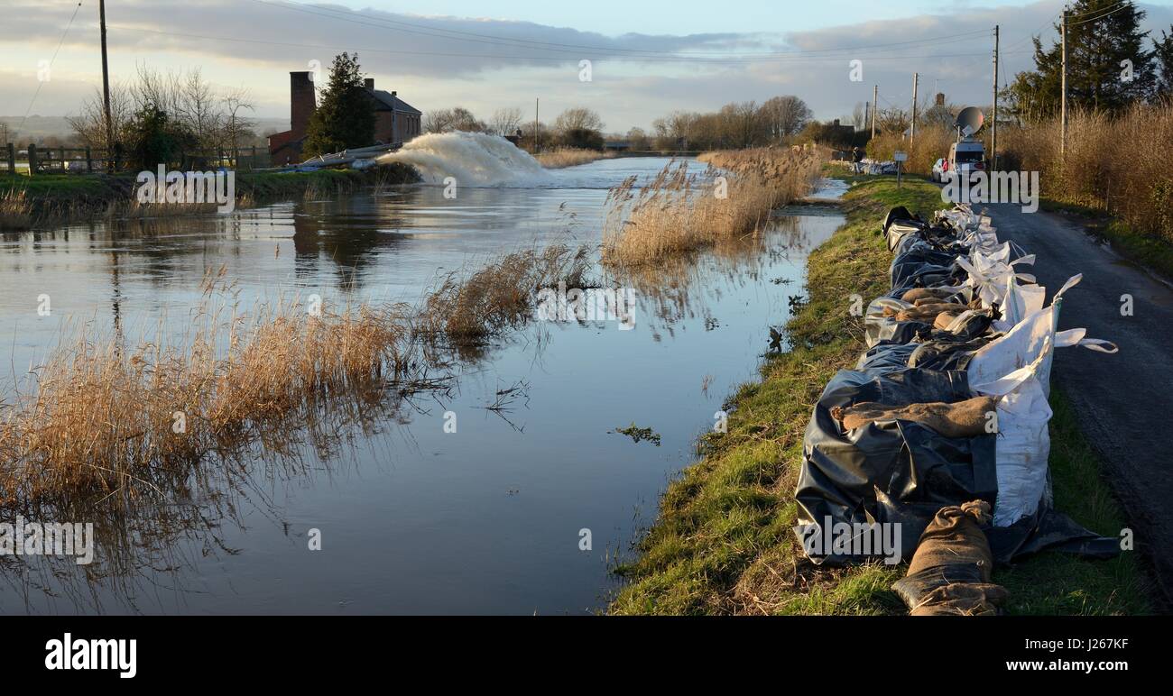 Swollen Parrett river with banks augmented with sand bags and pumps in action draining farmland, Burrowbridge, Somerset Levels, UK, February 2014. Stock Photo