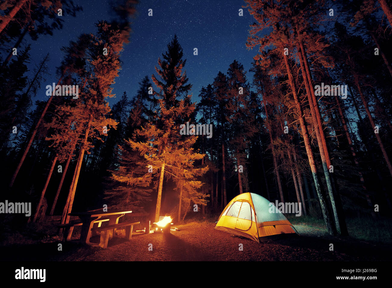 Camping under stars with bonfire and tent in Banff National Park Stock