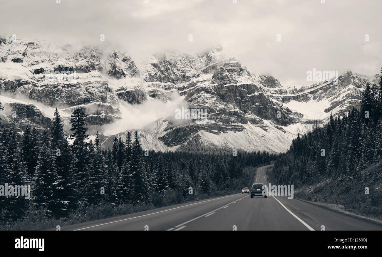 Highway with snow capped mountain forest and car in Banff National Park, Canada Stock Photo
