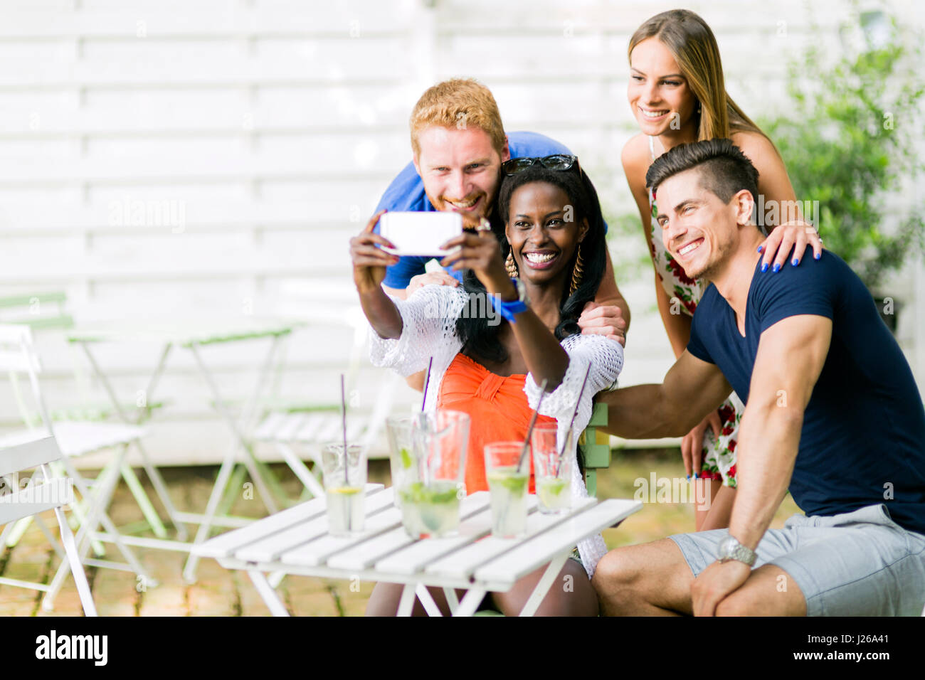 A group of friends sitting a table and talking smiling while taking ...