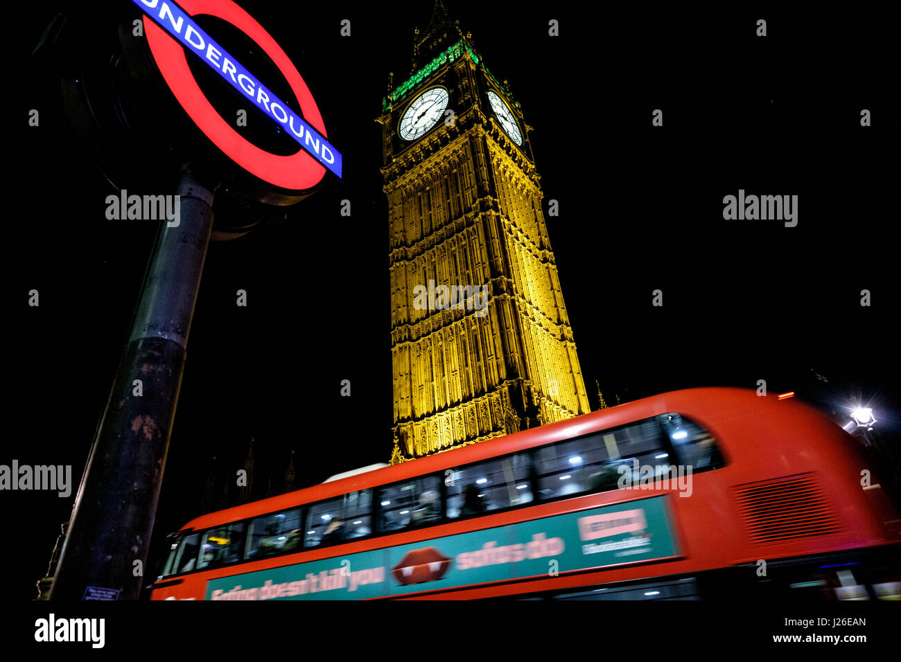 Public transport in London - Bus passing by an Underground station sign and the Big Ben Stock Photo