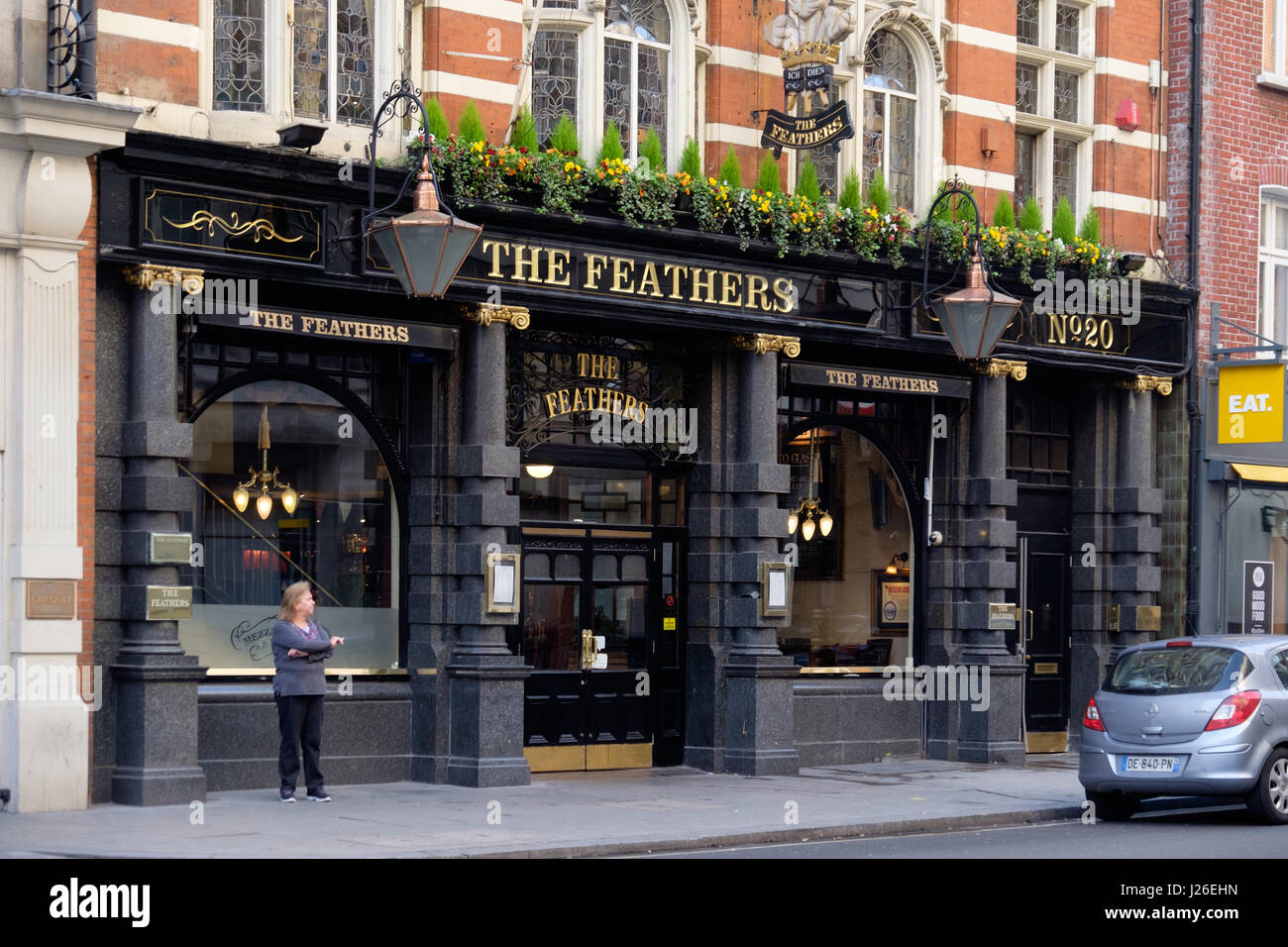 Woman smoking outside The Feathers pub in London, England, UK, Europe Stock Photo